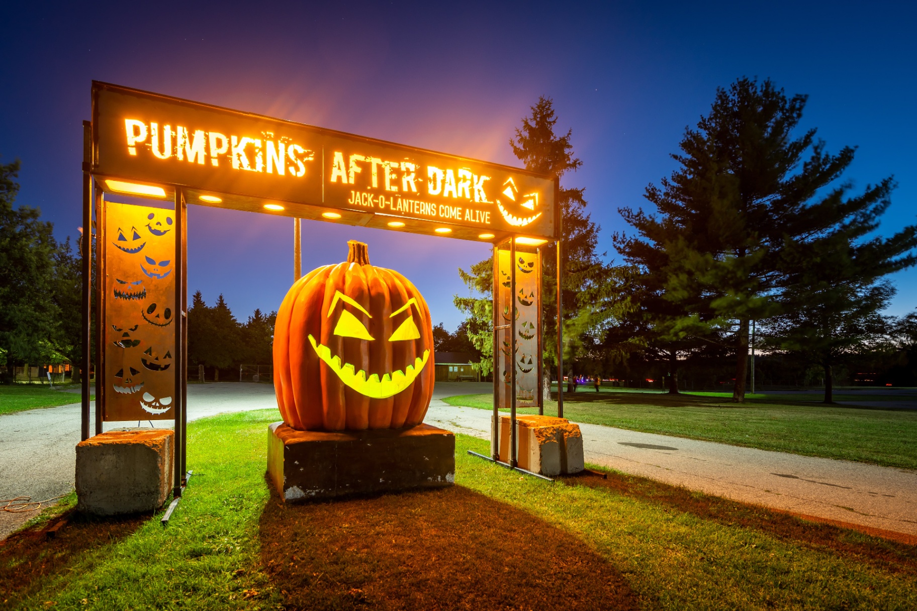 The glowing Pumpkins After Dark entry arch at dusk with a giant jack-o'-lantern